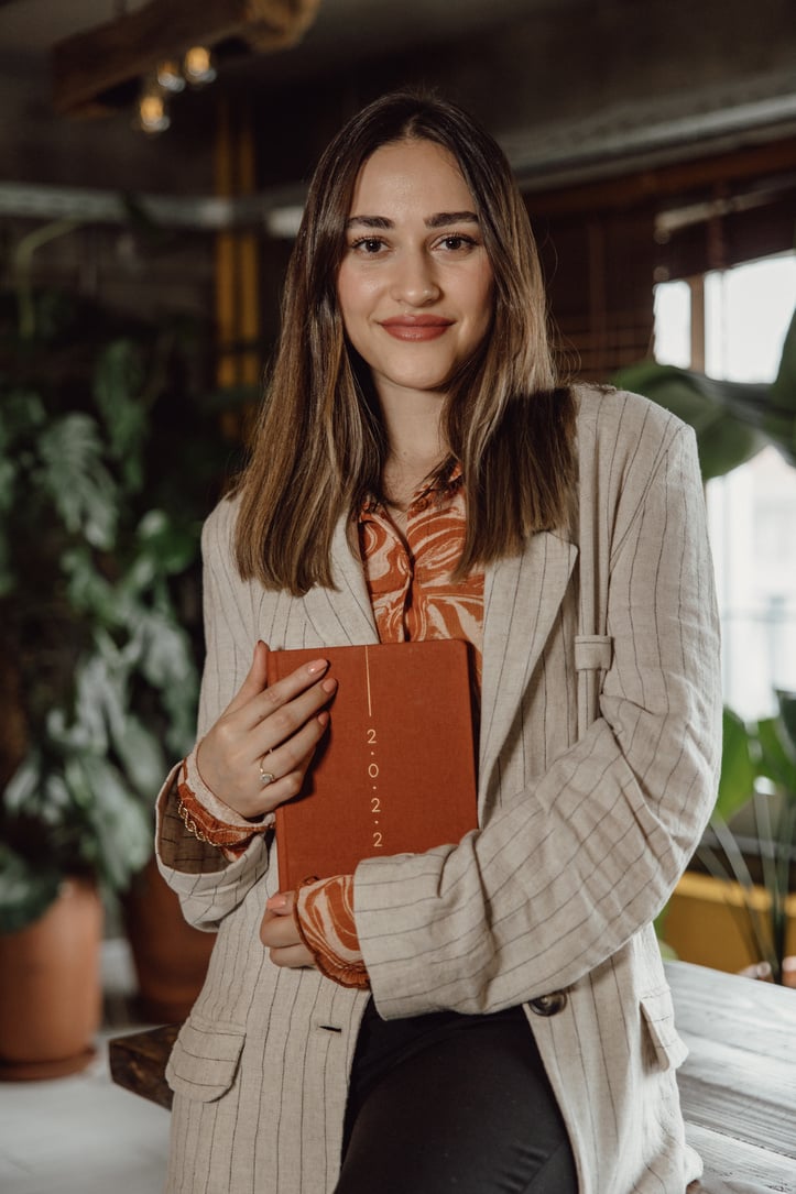 a person with long hair holding an orange notebook